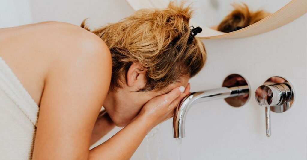 Adult woman washing her face at a modern bathroom sink during the morning routine.